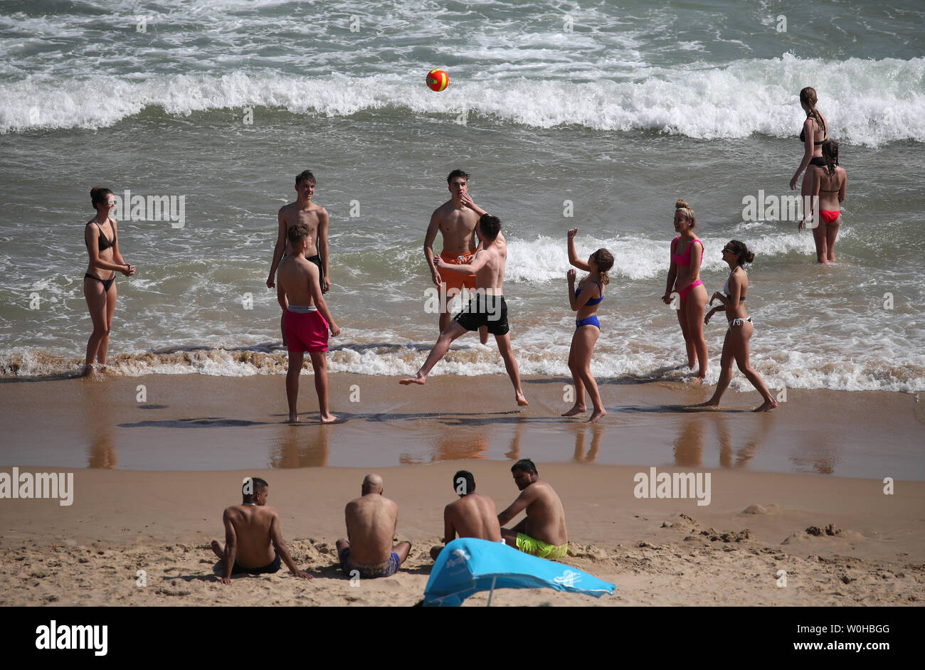 Menschen spielen Beachvolleyball, als sie das warme Wetter in Bournemouth in Dorset genießen. Stockfoto