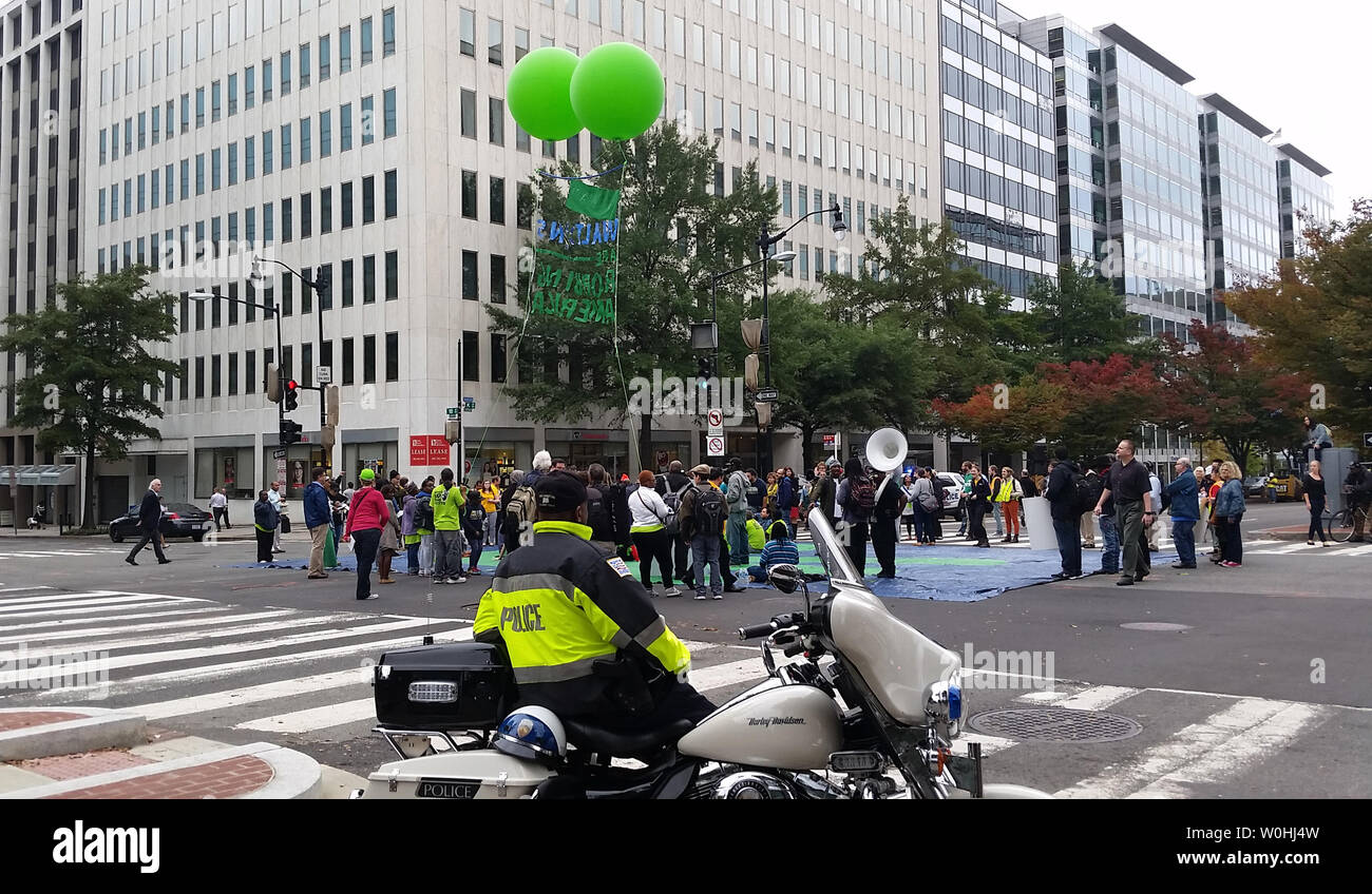 Polizei beobachten Demonstranten fordern höhere Löhne für Walmart Arbeiter, wie sie in der Mitte der K Street in der Innenstadt von Washington, DC am 16. Oktober 2014 sitzen. Der Protest außerhalb der Walton Family Foundation an der K Street und 18. Straße blockierten die Straßen für mehr als eine Stunde führen zu massiven Staus ein paar Blöcke vom Weißen Haus entfernt. 16 Demonstranten wurden festgenommen. UPI/Pat Benic Stockfoto