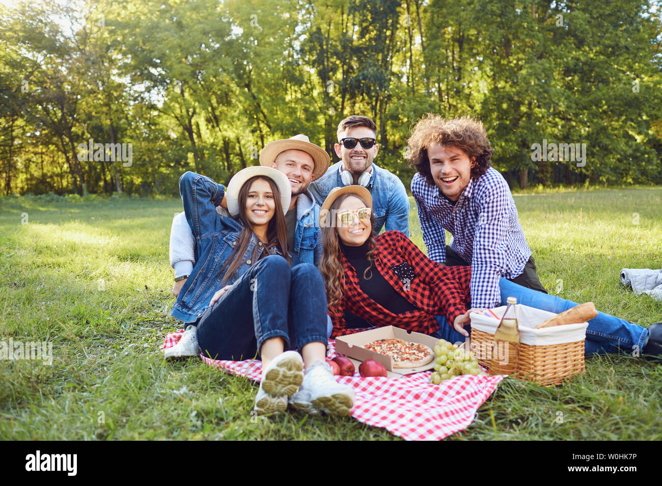 Eine Gruppe von Menschen sitzen auf dem Gras auf einem Picknick. Stockfoto