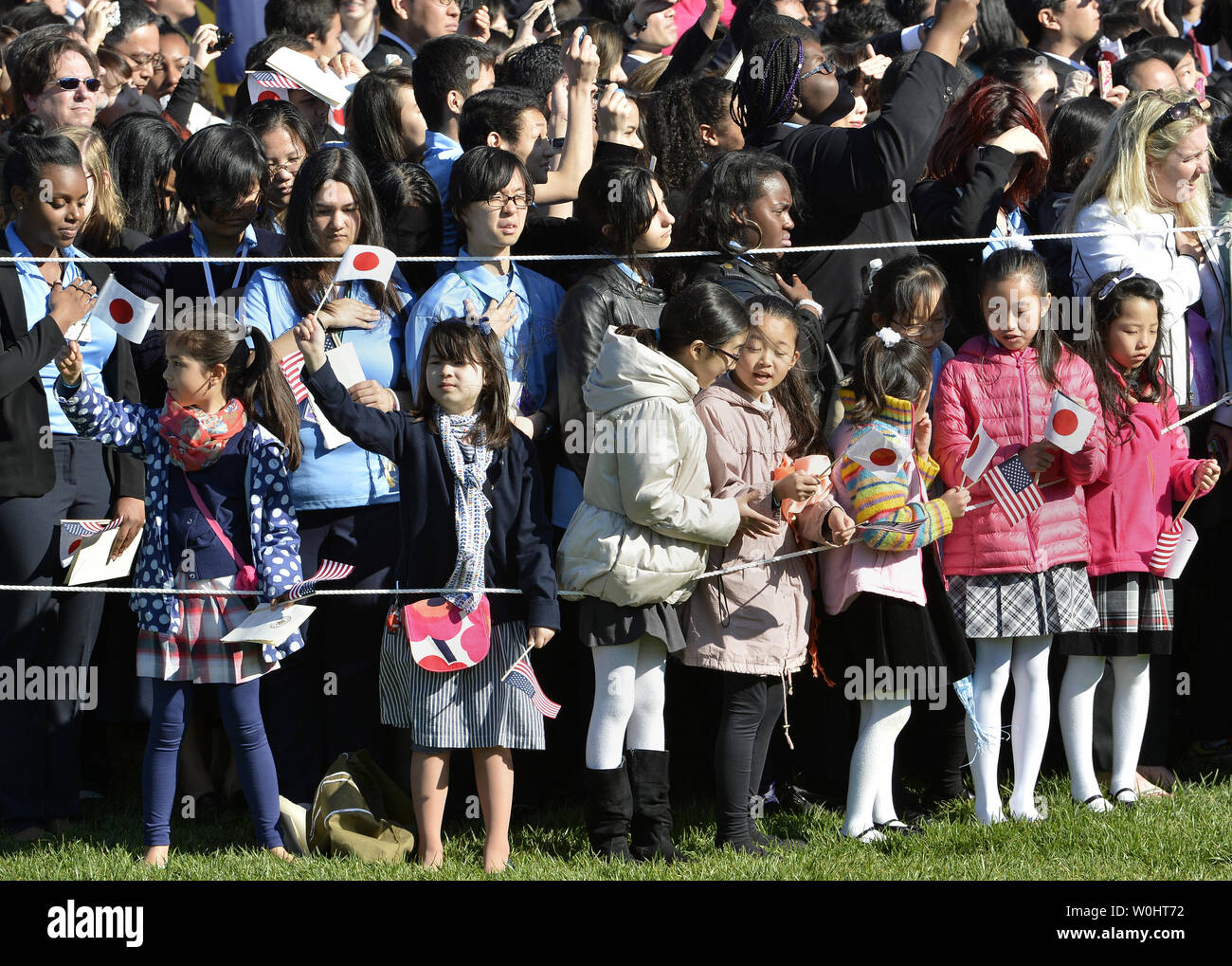 Kinder wave Amerikanische und Japanische Flaggen, wie sie die Ankunft der japanische Premierminister Shinzo Abe und seine Frau Akie Abe zu einem Begrüßungszeremonie auf dem Rasen des Weißen Hauses, 28. April 2015 in Washington, DC, erwarten. Foto von Mike Theiler/UPI Stockfoto