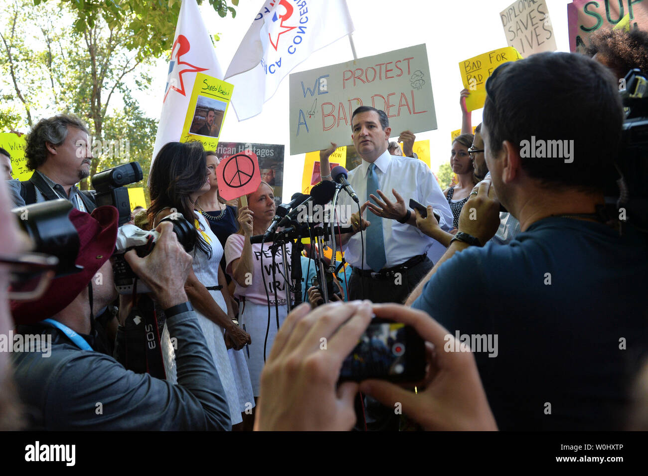 Präsidentschaftskandidaten Senator Ted Cruz (R-TX) wird durch Demonstranten schwärmten, wie er auf einer Kundgebung kritisierte nuklearer Deal der Obama-Regierung, die mit dem Iran für die Freilassung von vier amerikanischen Geiseln, in Washington, D.C. am 23. Juli 2015 spricht. Die protestgruppe Codepink protestiert bei der Veranstaltung zur Unterstützung des Iran befassen. Foto von Kevin Dietsch/UPI Stockfoto