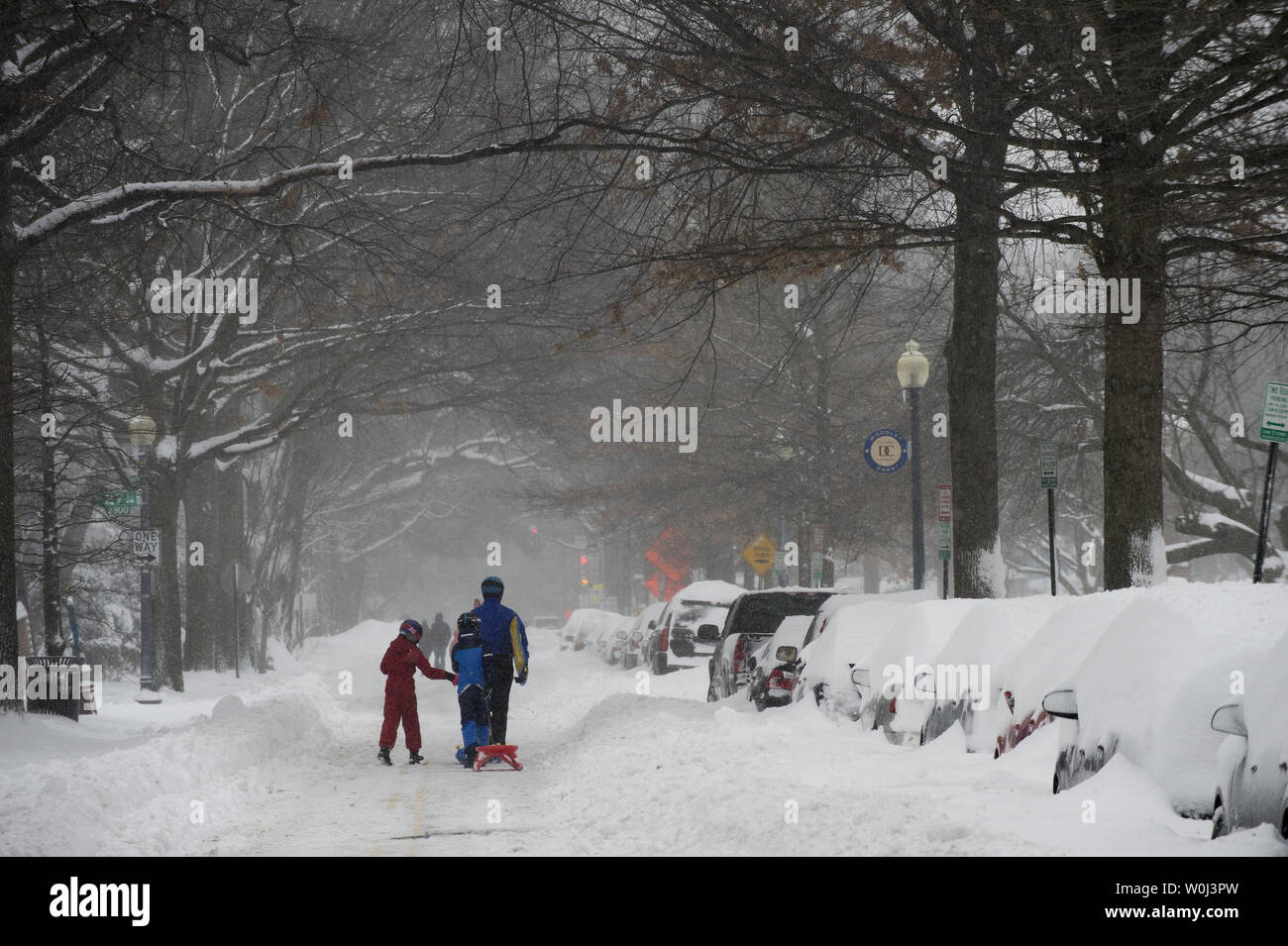 Eine Familie geht eine Straße im Nordwesten von Washington, DC, während einer Pause im Blizzard, die mehr als 20 cm Schnee auf die Hauptstadt der Nation am 23. Januar 2016 fallen wird. Die massive Blizzard hat den größten Teil der Ostküste bis zum Stillstand mit starken Winden und mehr als 30 Zentimeter Schnee in einigen Bereichen vorhergesagt. Foto von Pat Benic/UPI Stockfoto