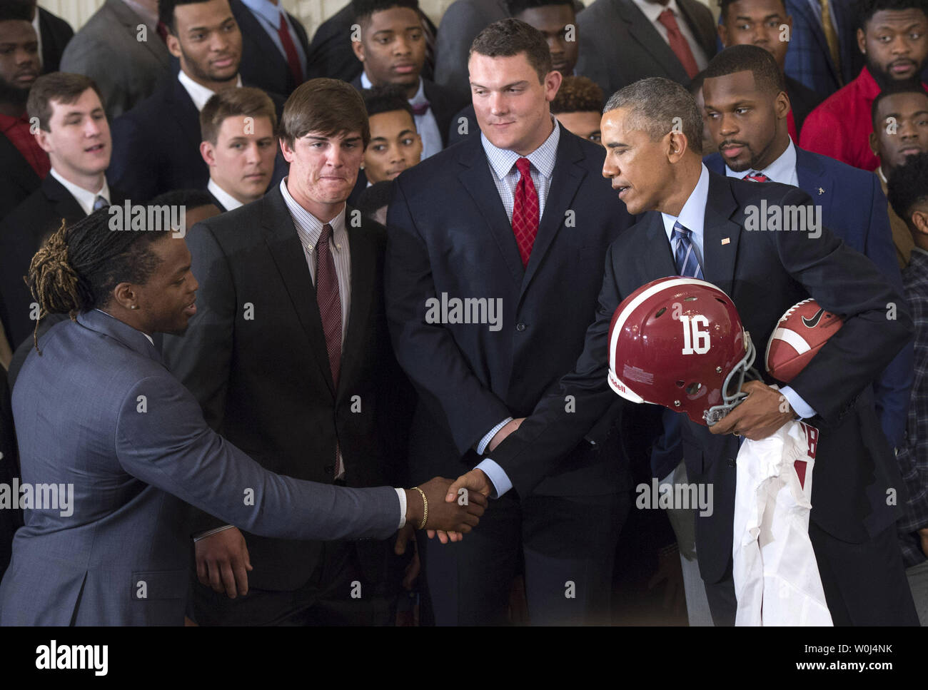 Präsident Barack Obama schüttelt Hände mit 2015 Heinemann Trophy Sieger Derrick Henry, wie Henry und andere Team Kapitän Präsident Obama einen Helm ein Trikot als Obama ehrt den 2015 - 2016 College Football Endspiel nationaler Meister Alabama Crimson Tide, im Osten Zimmer im Weißen Haus in Washington, D.C. am 2. März 2016. Foto von Kevin Dietsch/UPI Stockfoto
