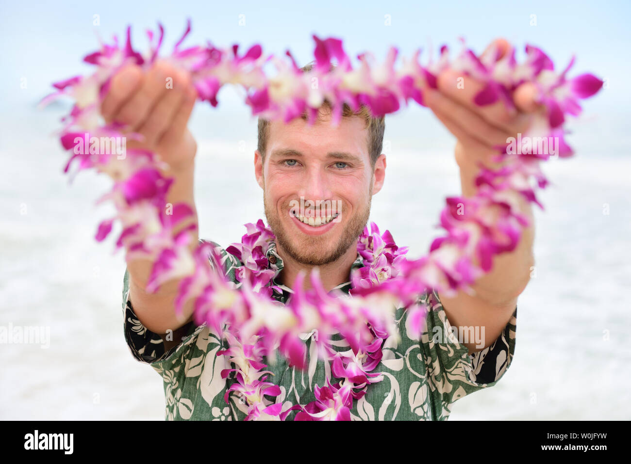 Hawaii kaukasischen Mann mit Willkommen Hawaii Lei. Männliche touristische Portrait holding Blume Halskette in der Kamera als Begrüßungsangebot für Tourismus in Hawaii. Reise Urlaub Konzept. Stockfoto