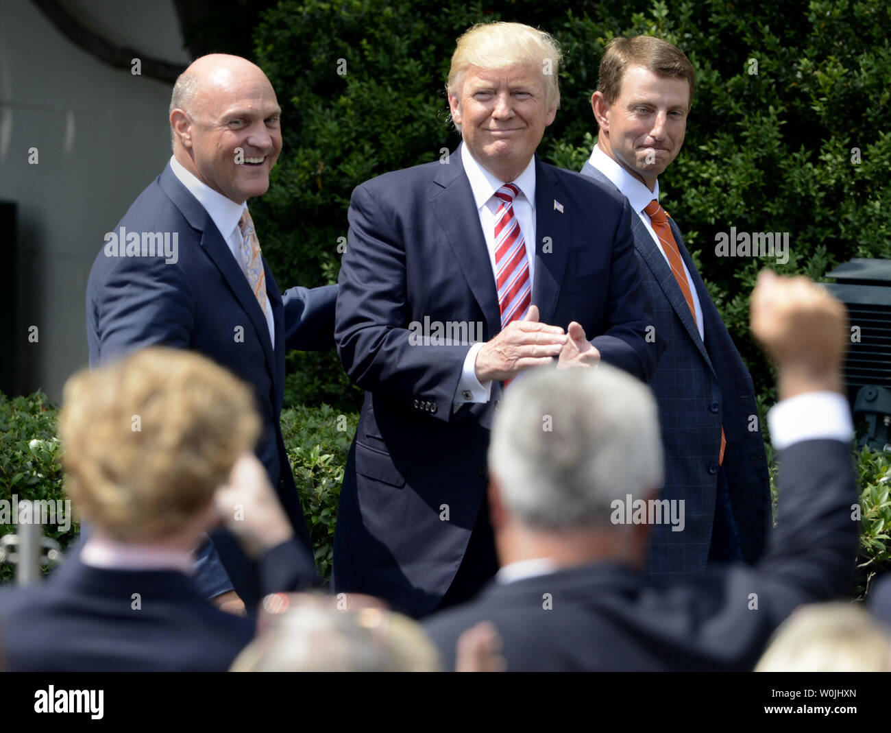 Präsident Donald Trump (C) erkennt einen Jubelnden Gast, wie er mit der Clemson Kopf kommt Trainer Dabo Swinney (R) und Universität Präsident James Clements Mitglieder der 2016 NCAA Football National Champions zum Weißen Haus, Juni 12, 2017, in Washington, DC, begrüßen zu dürfen. Foto von Mike Theiler/UPI Stockfoto