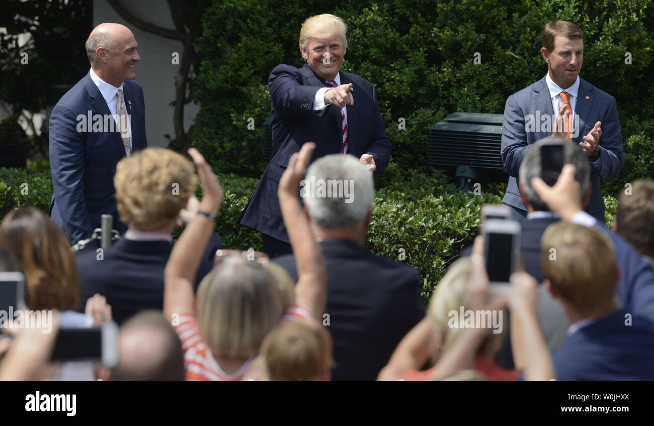 Präsident Donald Trump (C) erkennt jubelnde Gäste, wie er mit der Clemson Kopf kommt Trainer Dabo Swinney (R) und Universität Präsident James Clements Mitglieder der 2016 NCAA Football National Champions zum Weißen Haus, Juni 12, 2017, in Washington, DC, begrüßen zu dürfen. Foto von Mike Theiler/UPI Stockfoto
