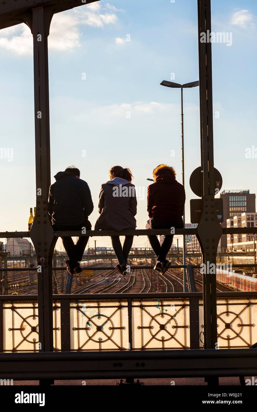 Drei jugendliche Sitzen auf dem Geländer der Haccurbrucke Brücke über die Gleise in die Ferne, Back Light, München suchen, Obere Stockfoto