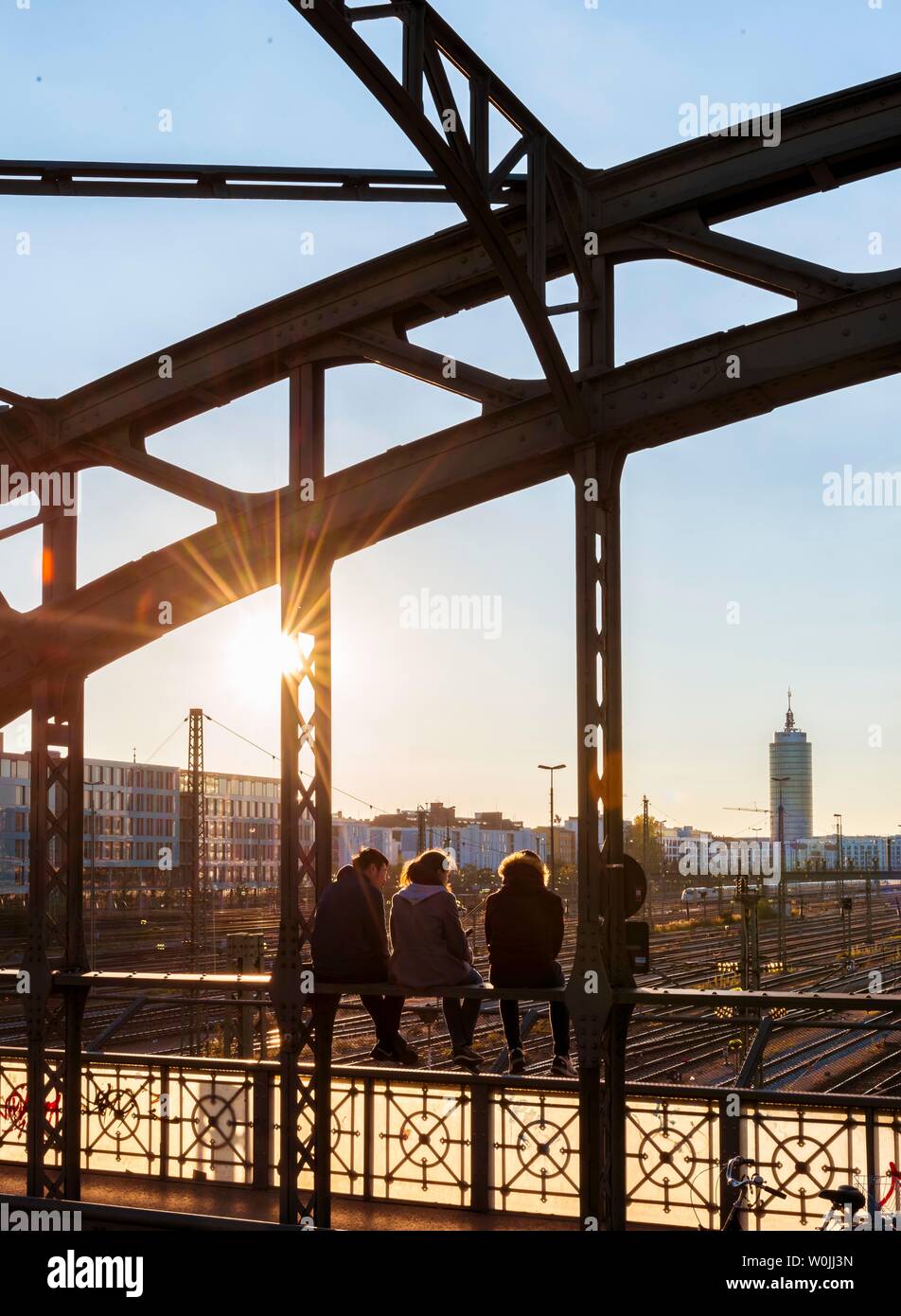 Drei jugendliche Sitzen auf dem Geländer der Haccurbrucke Brücke über die Gleise in die Ferne, Back Light, München suchen, Obere Stockfoto