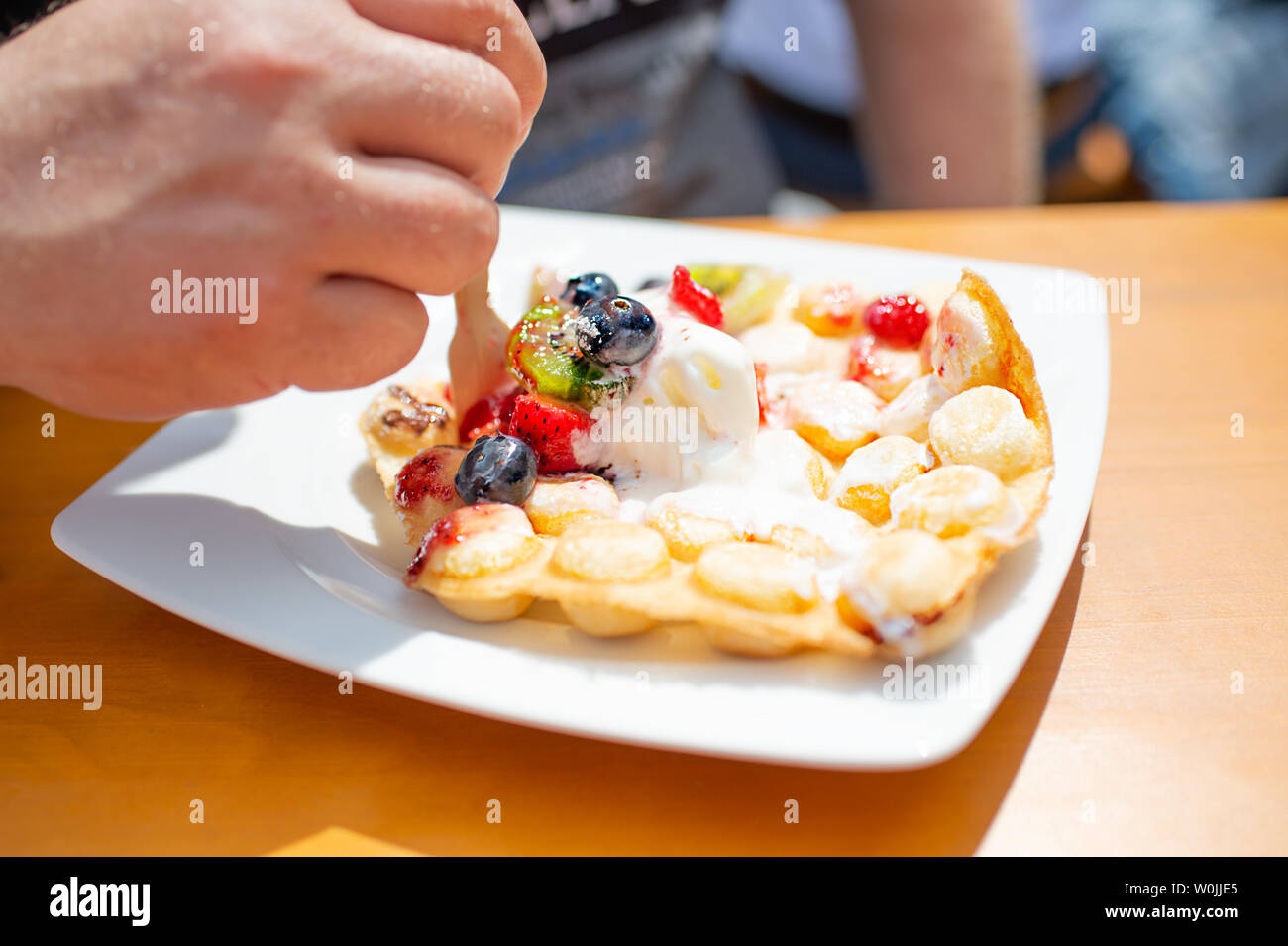 Trend Gebäck Bubble Waffeln (Ei Waffeln, Hong Kong Kuchen) mit Eis und frischen Früchten. Erdbeeren, Kiwi, Heidelbeeren, erdbeersauce auf Weiß Stockfoto