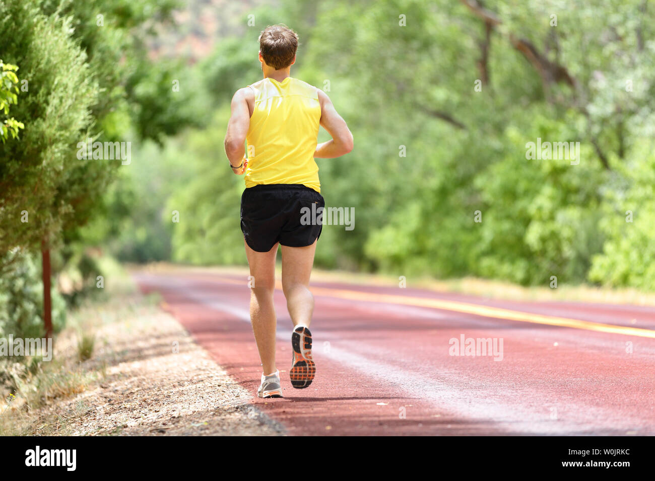 Laufender Mann Läufer joggen für Fitness und Gesundheit. Männliche Athleten auf Arbeiten auf Run tragen Sport Laufschuhe und Kurzschlüsse in Training für Marathon. Voller Körper Länge Ansicht zurück. Stockfoto