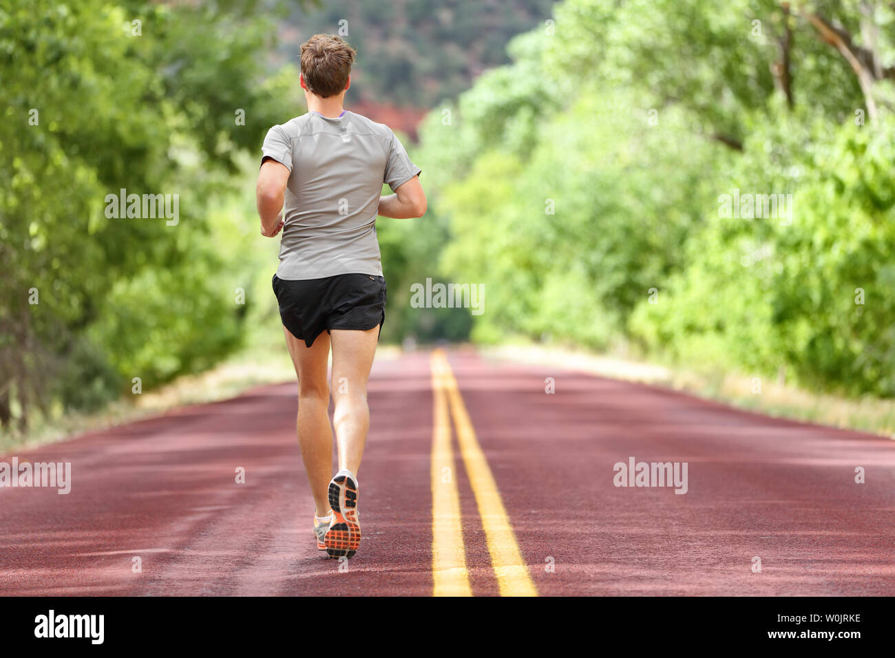 Männliche Läufer laufen auf der Straße Training für Fitness. Mann tut jogging Training laufen im Sommer im Freien in der Natur. Athleten in die Schuhe und Hosen Arbeiten für Marathon. Stockfoto