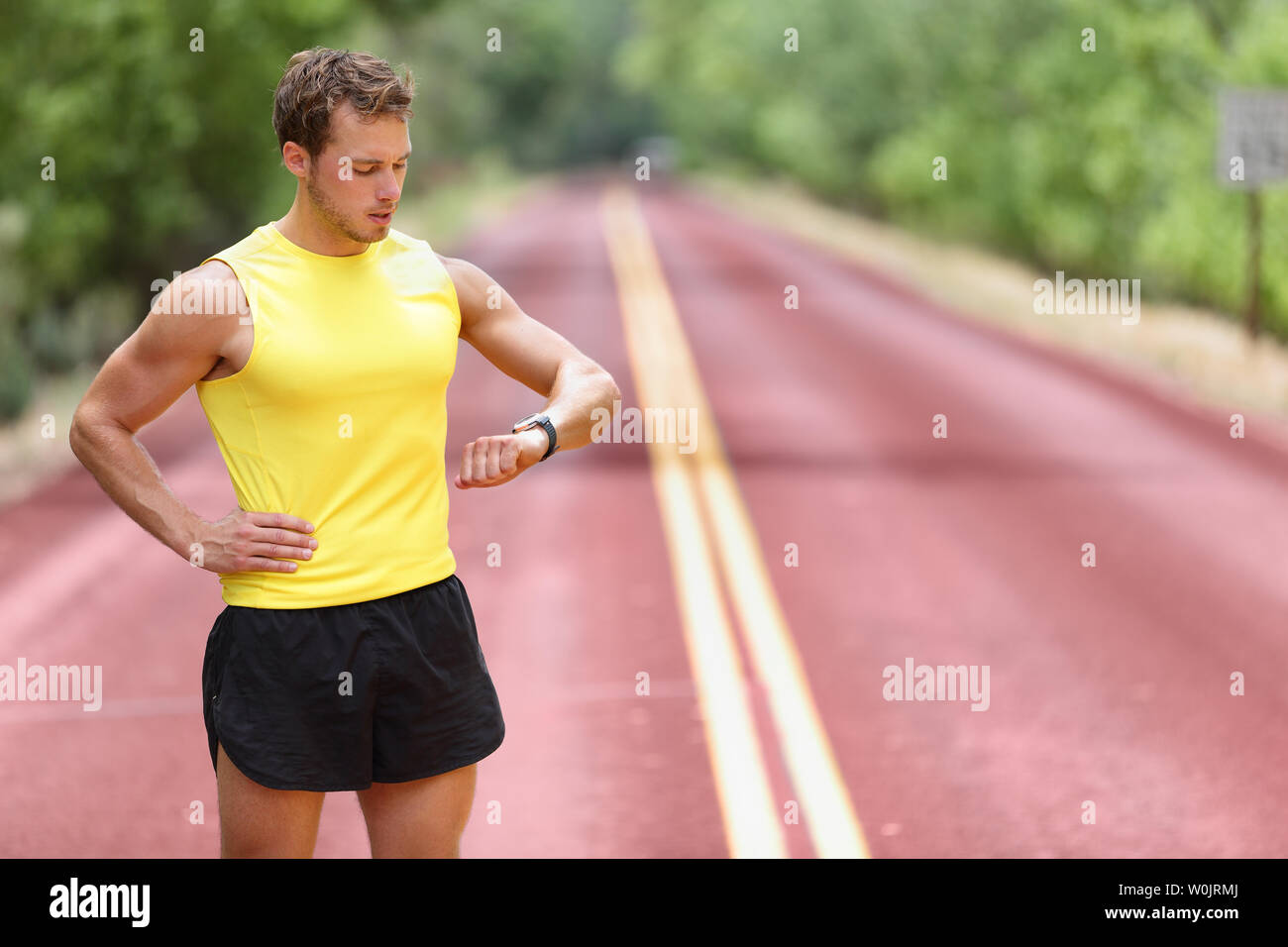 Runner suchen bei smartwatch Pulsmesser in Pause während der Ausführung.  Man joggen außerhalb Suchen bei Sport smart Watch während des Trainings  Training für Marathon. Passen männlich fitness Modell in seiner 20  Stockfotografie -