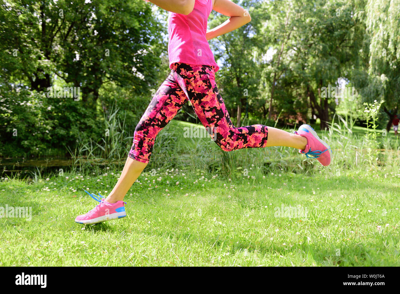 Läuferin Laufschuhe und Beine im City Park. Frau joggen tragen Blumen Capri Leggings compression Tights und rosa Laufschuhe. Stockfoto