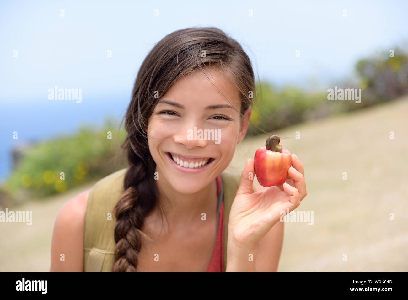 Mädchen mit natürlichen frischen Cashew-nuss Apfel Obst. Asiatische chinesische Frau Porträt Lächeln Holding einen frisch gepflückten Apfel Obst von den tropischen Baum, von wo aus die Cashew-nuss kommen. Karibisches essen. Stockfoto