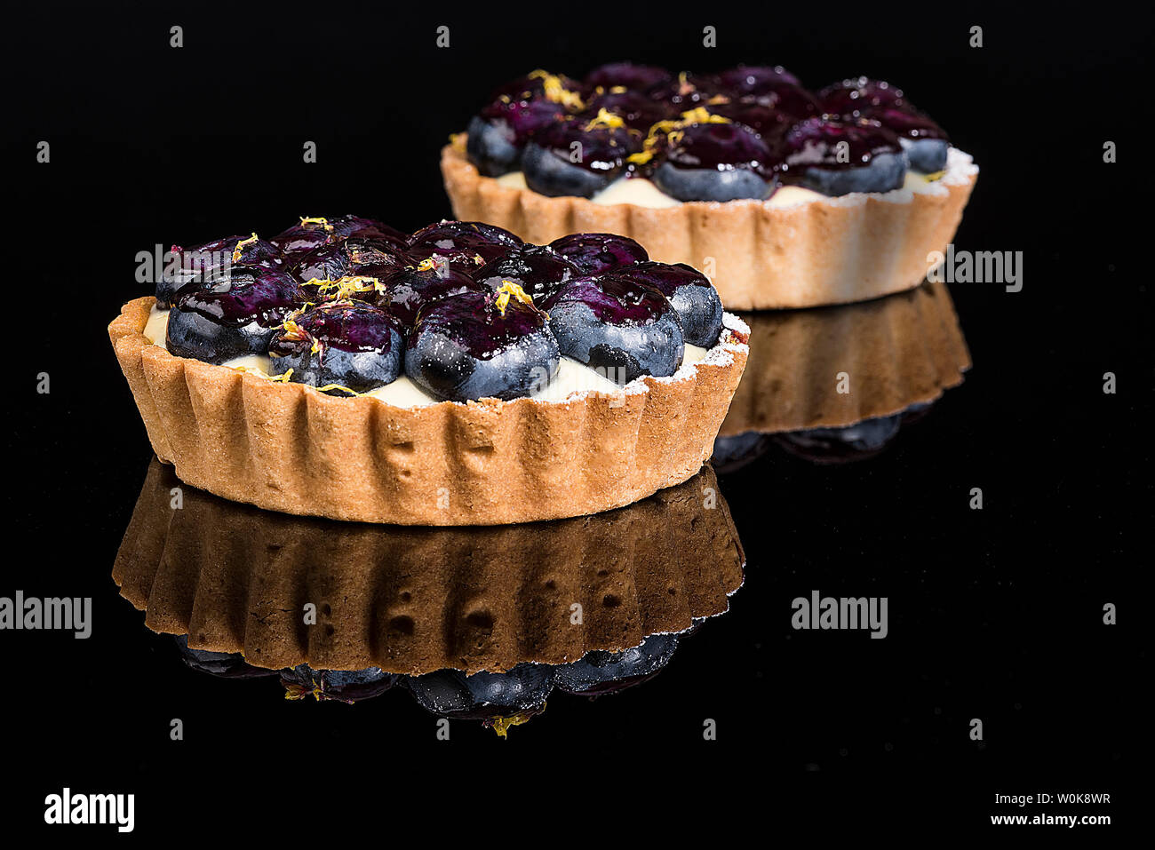 Zwei blueberry Torten auf schwarzem Granit mit Reflexionen Stockfoto