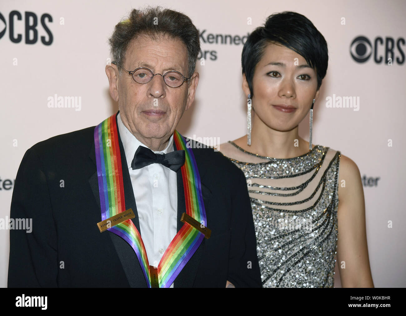 2018 Kennedy Center honoree Komponist Philip Glass (L) und sein Partner Saori Tsukada posieren für die Fotografen auf dem roten Teppich, wie sie für die Gala im Kennedy Center, Dezember 2, 2018, in Washington, DC. Die Ehrungen werden jährlich Künstler für ihr Lebenswerk in der Kunst und Kultur verliehen. Foto von Mike Theiler/UPI Stockfoto