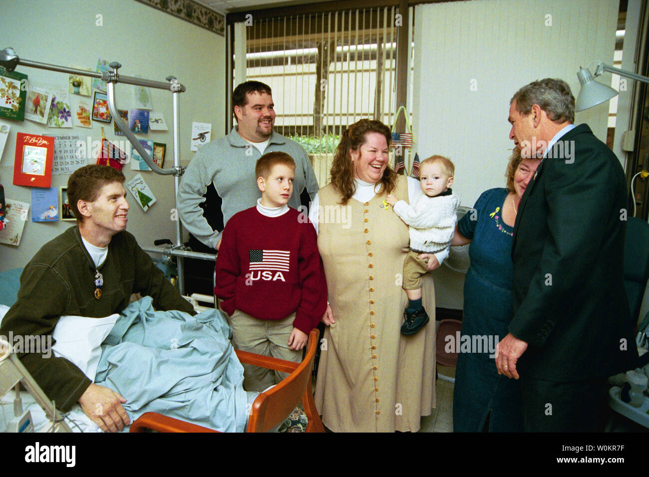 Präsident George W. Bush umfasst die Schwiegermutter von U.S. Army Staff Sergeant Roy Mitchell, Links, wie andere Familienmitglieder während des Präsidenten Besuch Walter Reed Army Medical Center in Washington, D.C., Donnerstag, 18. Dezember 2003. Präsident Bush hatte gerade Sgt vorgestellt. Mitchell die Lila Herz für Verletzungen, während im Irak dienen. Sgt. Mitchell ist aus Mailand, Indiana. Andere Familie Mitglieder, von links, Jerry Stoneking, Zachiary Bice und Michelle Mitchell, der Betrieb des Mitchell Sohn Jerrett. (UPI Foto/Eric Draper/Weiße Haus) Stockfoto