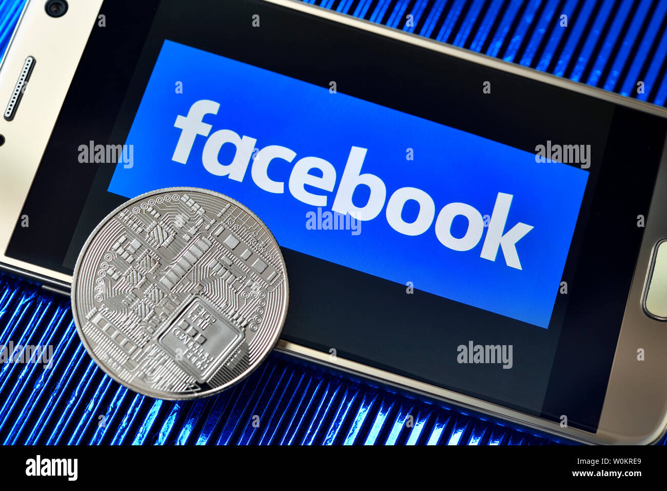 Facebook Logo auf einem Bildschirm des Smartphones und Münze, Waage cryptocurrency Stockfoto