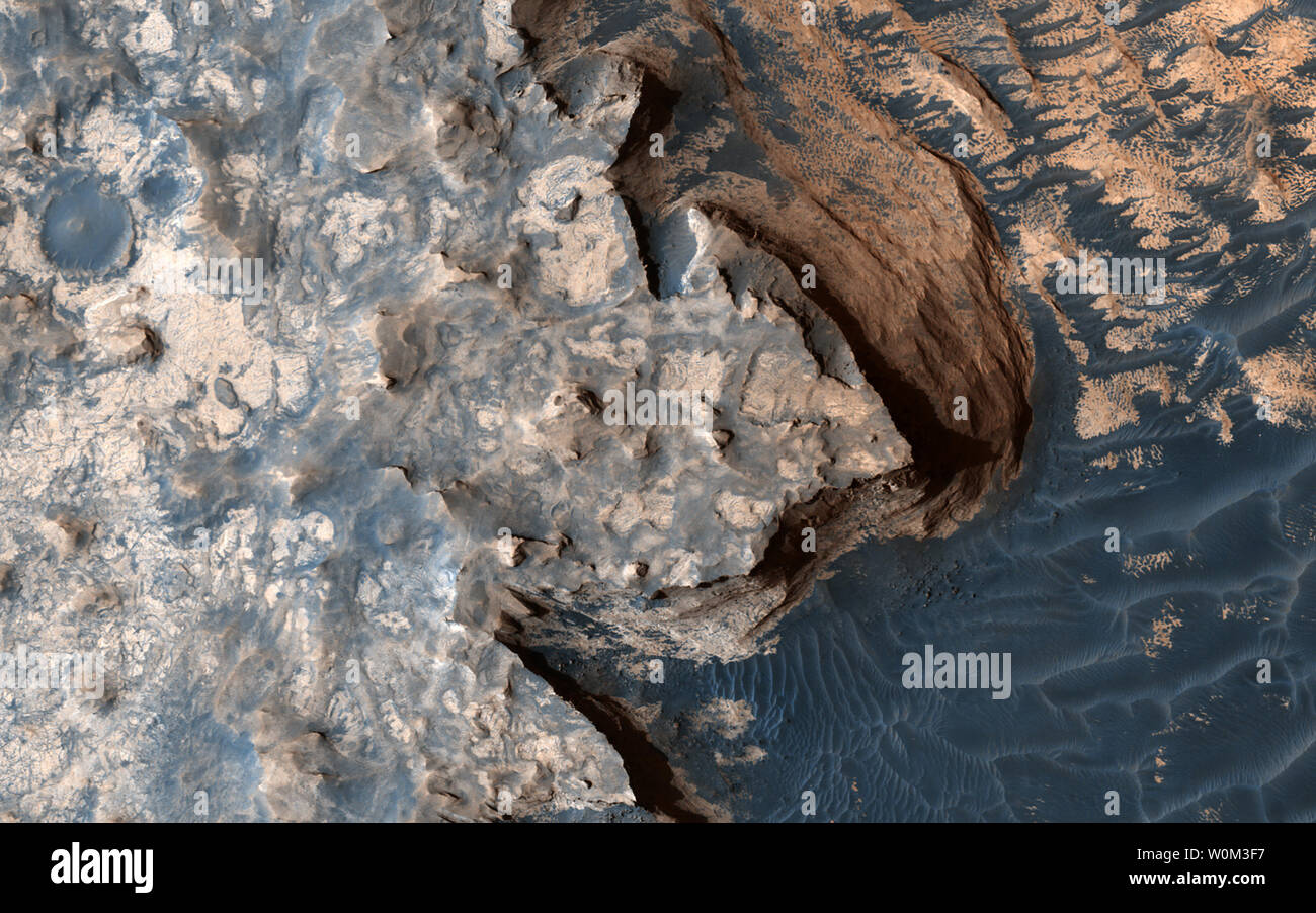 Dieses Bild wurde von der High Resolution Imaging Science Experiment (HiRISE)-Kamera an Bord der NASA Mars Reconnaissance Orbiter am 18. April 2017, um 14:04 Uhr Ortszeit Mars aufgenommen. Eine Nahaufnahme in Erweiterte Farbe erzeugt eine durchschlagende Wirkung, die den Eindruck von einer Wolke bedeckte Klippe mit schäumenden Wellen, die gegen ihn. Die Realität ist, dass die Oberfläche des Mars viel trockener ist als unsere Vorstellungen vielleicht vorschlagen möchten. Dies ist nur ein kleiner Teil einer viel größeren Struktur; ein umgekehrtes Krater - ein Krater, der verfüllten Material gewesen ist, die resistenter gegen Erosion als den Felsen herum ist Stockfoto