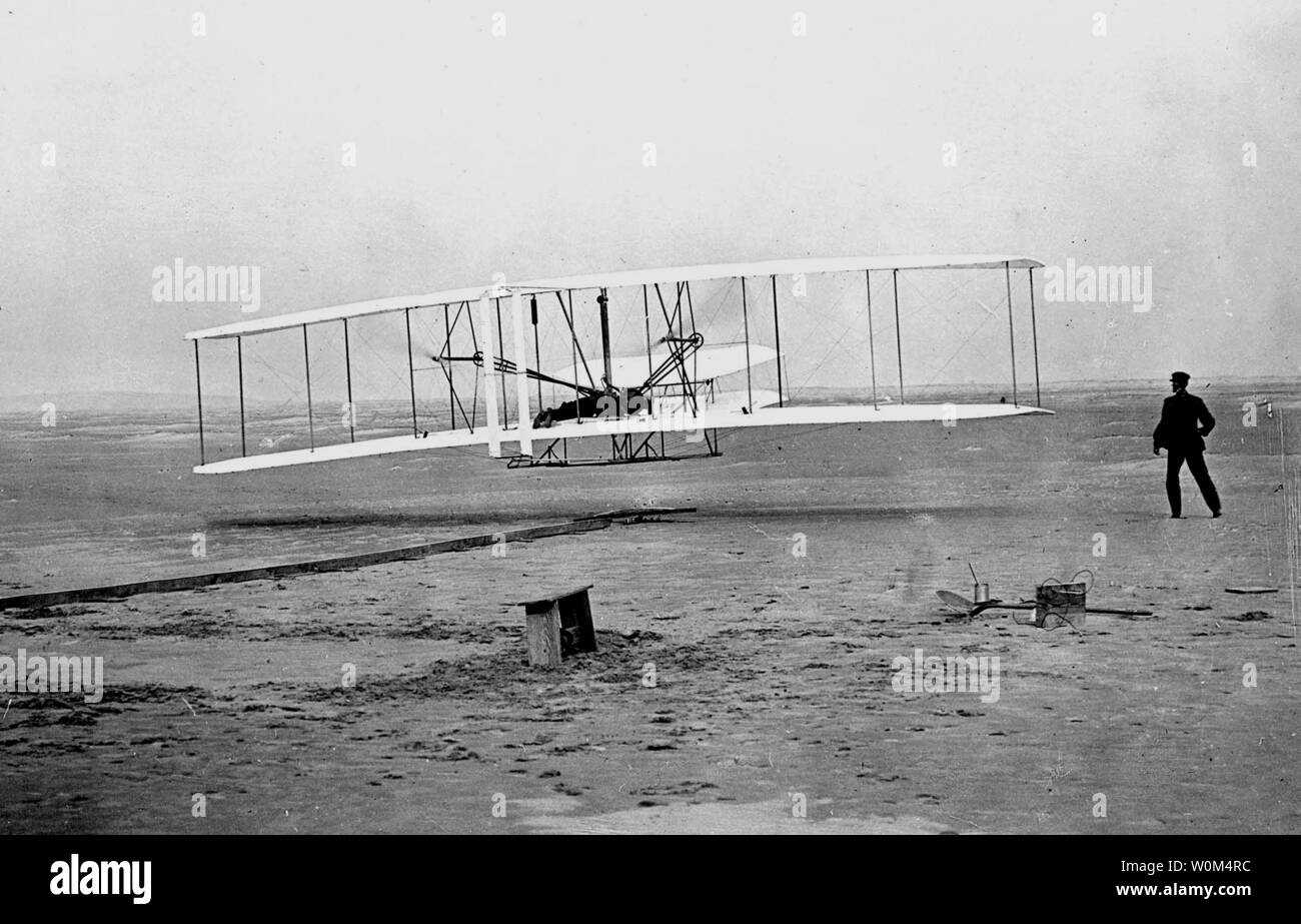 Orville Wright Piloten den ersten Flug als Bruder Wilbur läuft neben um 10:35 Uhr Am 17. Dezember 1903 in Kitty Hawk, North Carolina. Das Flugzeug hatte gerade die Spur für einen Flug, der 12 Sekunden gedauert und ging über 120 Meter links. Das klassische Bild von vor 100 Jahren wurde von John Daniels nach Erhalt eine schnelle Fotografie Lektion von Orville. Es war das einzige Bild, das jemals von Daniels, ein Mitglied der in der Nähe Kill Devil Hills lifesaving Station übernommen. (UPI Foto/John Daniels) Stockfoto