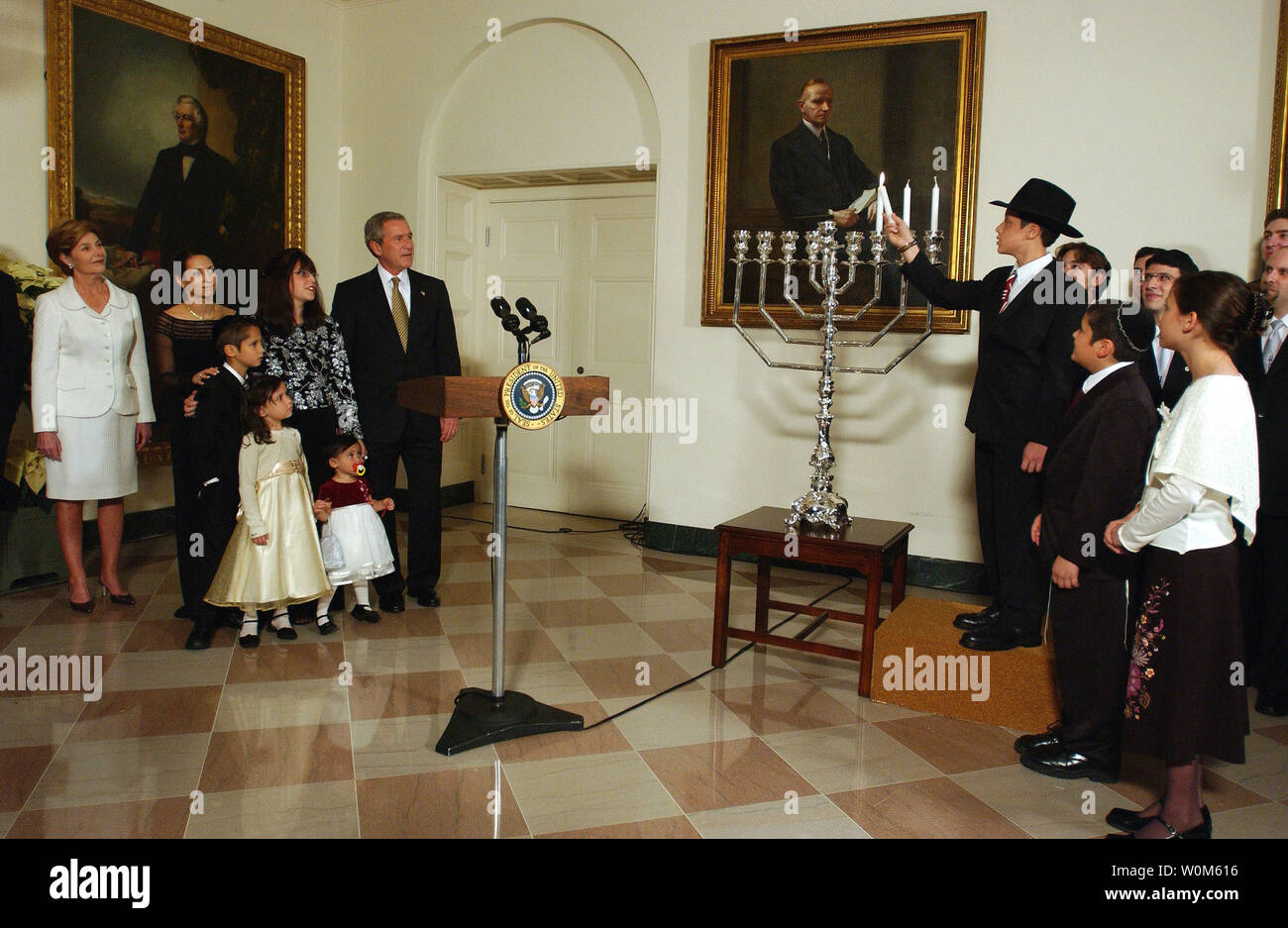 In den letzten drei Jahren, hat der Präsident in einem Menorah lighting vor der jährlichen Weiße Haus Hanukkah Empfang teilgenommen. Am Recht, Menachem Felzenberg leuchtet die Chanukah Menorah als seine Geschwister, Chaim, und Miriam Blick auf drei der sechs Felzenberg Kinder. Auf der linken Seite sind Usa-Präsident George W. Bush und First Lady Laura Bush mit dem Rest der Felzenberg Familie. Ihr Vater, Kapitän Shmuel Felzenberg, dient im Irak als der ältere jüdische Kaplan mit 84Th der US Army Engineer Battalion, von Schofield Kasernen, Hawaii. Stockfoto