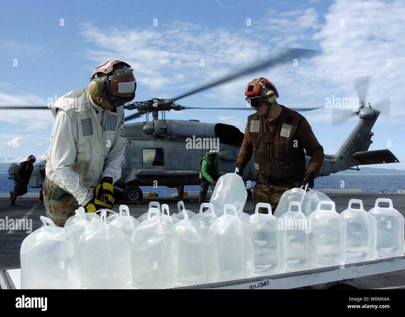 Segler bereiten Krüge des gereinigten Wassers in eine SH-60B Seahawk zu laden, die den aberhawks" der Hubschrauber Anti-Submarine Squadron Licht Vier Sieben (HSL-47) zugeordnet, auf dem Flugdeck an Bord der USS Abraham Lincoln (CVN 72) im Indischen Ozean am Jan. 11, 2005. (UPI Foto/Tyler J. Clements/US-Navy) Stockfoto