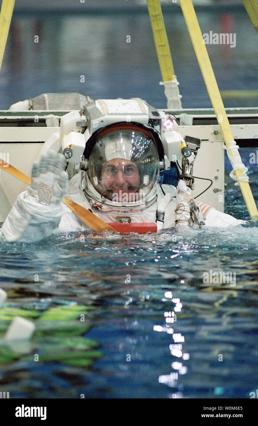 Astronaut Stephen K. Robinson, STS-114 Mission Specialist, gekleidet in einem Training Version der Extra Vehicular Mobility Unit (EMU) Raumanzug, Wellen, wie er in den Gewässern des Neutral Buoyancy Laboratory (NBL) in der Nähe des Johnson Space Center (JSC) eingetaucht ist. NASA plant Entdeckung irgendwann Ende Juli, wenn die siebenköpfige Return to Flight Crew auf der Internationalen Raumstation fliegen in erster Linie zu prüfen und neue Sicherheit Verfahren bewerten zu starten. Es hat viele Verbesserungen der Sicherheit zum Shuttle, einschließlich einer neu gestalteten Externen Tank, neue Sensoren und einem Boom, die Ast erlauben. Stockfoto