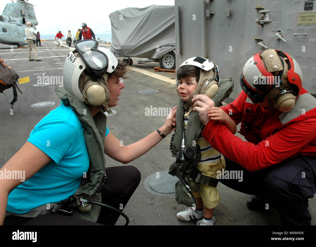 Eine Frau, die Komfort, wie ein kleines Kind nach der Ankunft an Bord der amphibious Transport dock USS Trenton LPD (14) mit dem Hubschrauber aus dem Libanon am 21. Juli 2006. USS Trenton und andere Schiffe, die Eigentum der Amphibisches Schiff USS Iwo Jima (LHD 7) Expeditionary Strike Group (ESG) auf Station 21. Juli angekommen, als Teil der Task Force 59, kommandiert von Brig. Gen. Carl Jensen, US Marine Corps. Auf Antrag der US-Botschafter in Libanon und an der Richtung des Verteidigungsministers, das United States Central Command und der 24 MEU unterstützen mit der Abreise von US-Bürgern aus dem Libanon. (UPI Pho Stockfoto