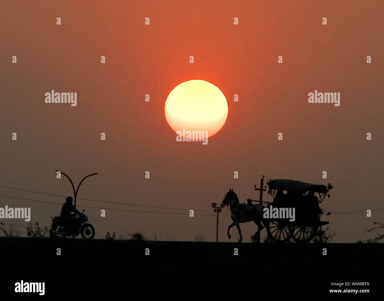 Ein Pferd, Kutsche und ein Motorrad fahren auf einer Straße bei Sonnenuntergang am Stadtrand von Neu Delhi, Indien Am 31. Januar 2008. (UPI Foto) Stockfoto