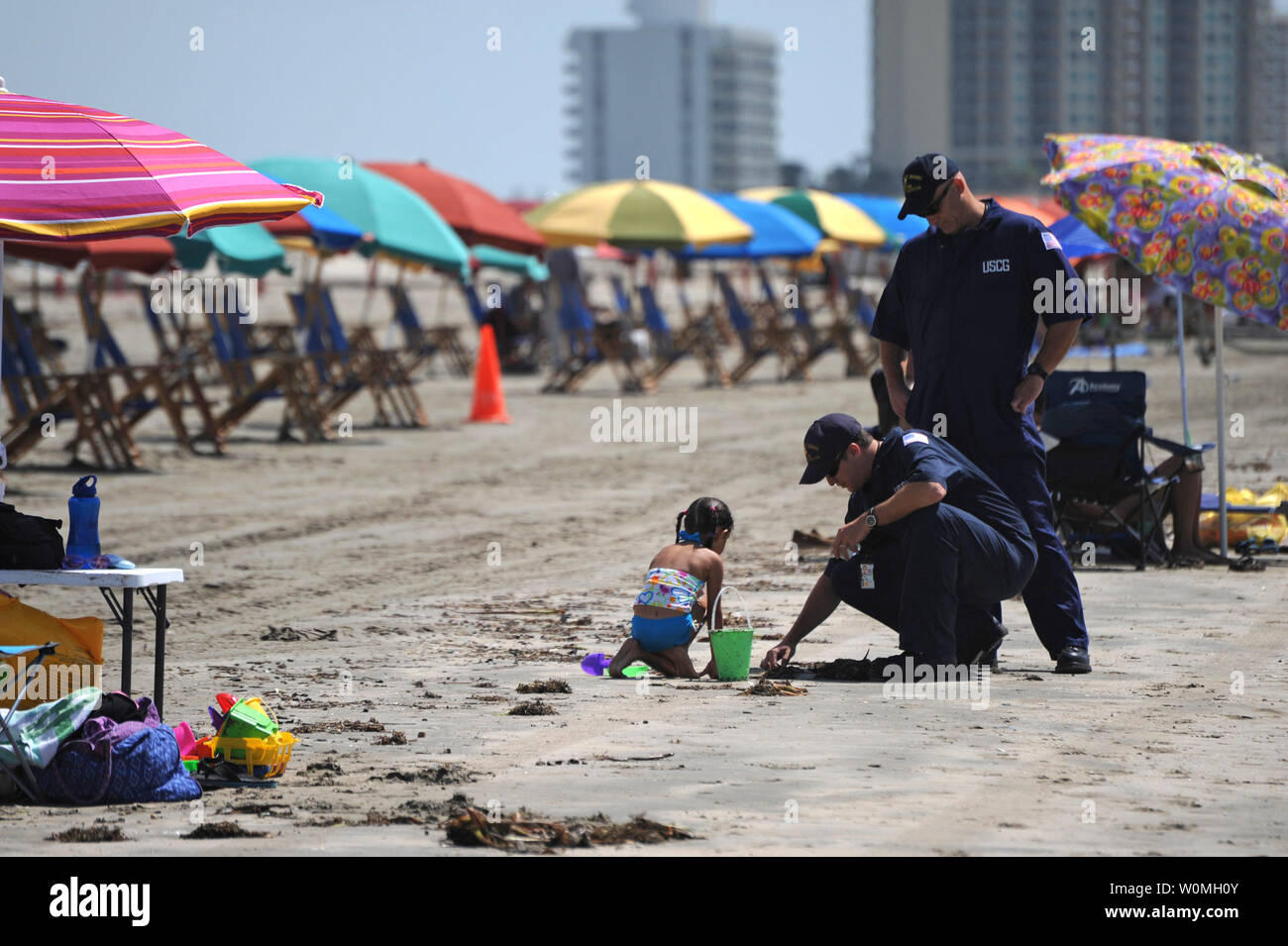 Petty Officer 1st Class Matt Fisher, kniend, und Petty Officer 1st Class James Huddleston, Marine science Techniker bei Coast Guard Sektor C Houston Galveston, prüfen eine mögliche Tarball auf der Stewart Beach als Strandurlauber, in Galveston, Texas, am 11. Juli 2010. Staatlichen, lokalen und föderalen Beamten haben Patrouillen entlang der Texas Küste als Reaktion auf Berichte über Tarballs waschen an Land gestiegen. UPI/Prentice Danner/U.S. Küstenwache Stockfoto