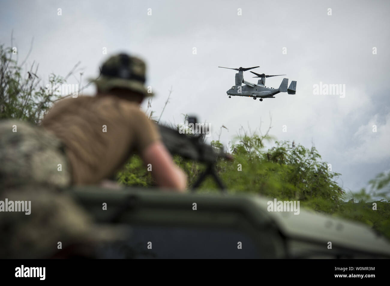 Engineering 3. Klasse Philip Rose, zugeordnet zu den Naval Mobile Konstruktion Bataillon (NMCB) 11, steht mit einer M-240 B Light Machine Gun (LMG) mit Leerzeichen geladen und Uhren a B MV-22 Osprey transport Marines 3 Bataillon zugeordnet, 3 Marines für eine Insel Beschlagnahme bohren während der Übung Valiant Shield 2016 in Tinian, Commonwealth der Nördlichen Marianen (Cnmi), 20. September 2016. Valiant Shield ist eine Biennale, US Air Force, Navy und Marine Corps Übung in Guam gehalten, die sich auf reale Kenntnisse bei der Aufrechterhaltung der teilstreitkräfteübergreifenden See, in der Luft, an Land und im Cyberspace. Ph Stockfoto