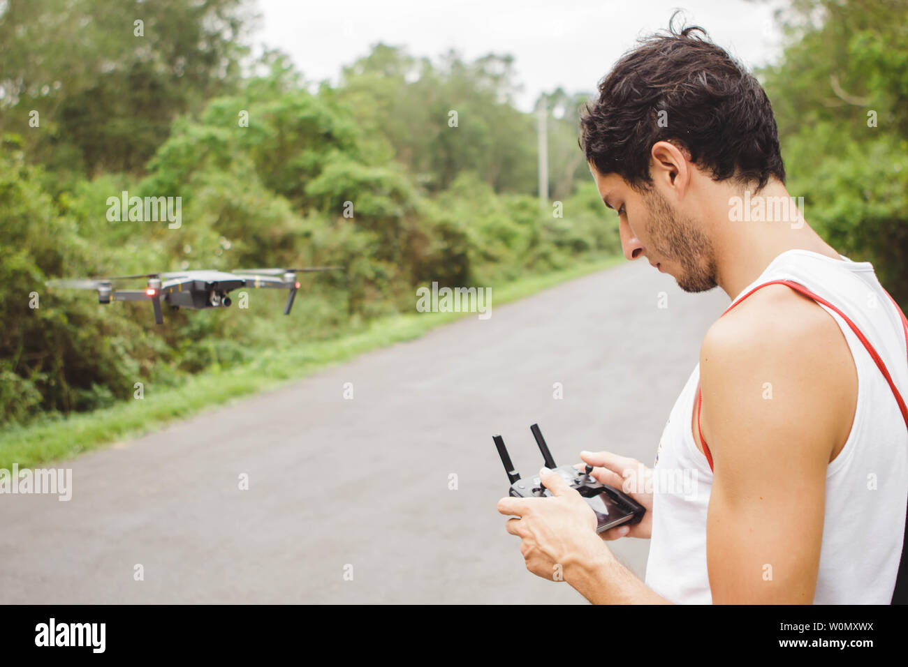 Junger Mann fliegen mit der Drohne in einer Straße Stockfoto