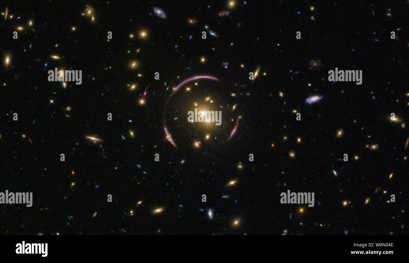 Die überwiegende Mehrheit dieser Flecken sind Galaxien, sondern an Ort und Stelle einen Vordergrund Star aus unserer Galaxie, können Sie für einen Punkt von Licht mit klatschsüchtige Beugung Spikes. Die verlockendsten Thema sitzt in der Mitte des Rahmens. Mit dem Namen SDSSJ 0146-0929, die glühende zentrale ausbuchtung ist ein Galaxienhaufen - eine monströse Sammlung von Hunderten von Galaxien alle zusammen in der unnachgiebige Griff der Schwerkraft gefesselt. Die Masse dieses galaxy Cluster ist groß genug, um es ernsthaft die Raumzeit verzerren, Erstellen der ungerade, looping Kurven, fast umschließen den Cluster. Diese anmutigen Bögen sind Beispiele für eine cosmi Stockfoto