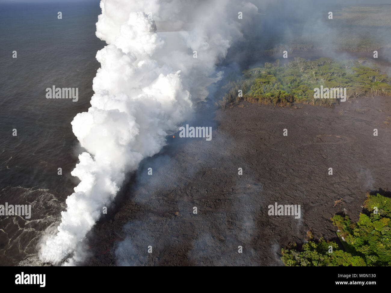 Anzeigen am 20. Mai 2018 getroffen, der fissur 20 Lavastrom erreichen der Ozean. Heiße Lava in das Meer schafft ein dichtes white Plume namens "faulenzen" (kurz für "lava Dunst'). Faulenzen Formen als heiße Lava kocht Meerwasser zu Trockenheit. Der Prozess führt zu einer Reihe von chemischen Reaktionen, die in der Bildung einer wehenden weißen Wolke aus einer Mischung von kondensierten Meerwasser Dampf Ergebnis, Salzsäure Gas, und kleine Scherben von vulkanischen Glas. Diese Mischung hat das Stechen und korrosiven Eigenschaften der Batterie Säure zu verdünnen. Da laze downwind ausgeblasen werden kann, seine ätzende Wirkungen können weit über die a Stockfoto