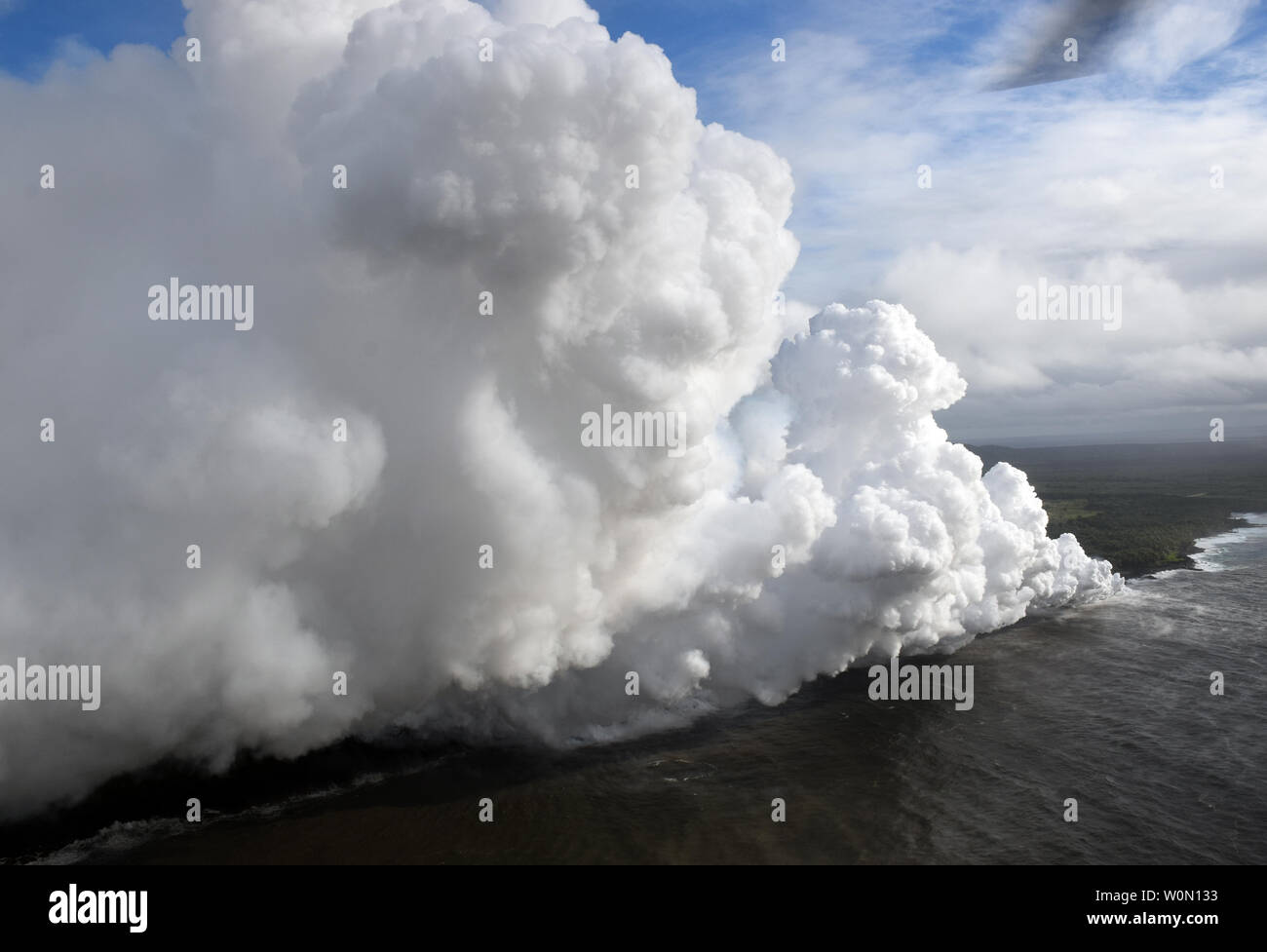 Anzeigen am 20. Mai 2018, durch die Lavaströme erreichen der Ozean. Heiße Lava in das Meer schafft ein dichtes white Plume namens "faulenzen" (kurz für "lava Dunst'). Faulenzen Formen als heiße Lava kocht Meerwasser zu Trockenheit. Der Prozess führt zu einer Reihe von chemischen Reaktionen, die in der Bildung einer wehenden weißen Wolke aus einer Mischung von kondensierten Meerwasser Dampf Ergebnis, Salzsäure Gas, und kleine Scherben von vulkanischen Glas. Diese Mischung hat das Stechen und korrosiven Eigenschaften der Batterie Säure zu verdünnen. Da laze downwind ausgeblasen werden kann, seine ätzende Wirkungen können weit über die eigentliche Ozean verlängern Stockfoto