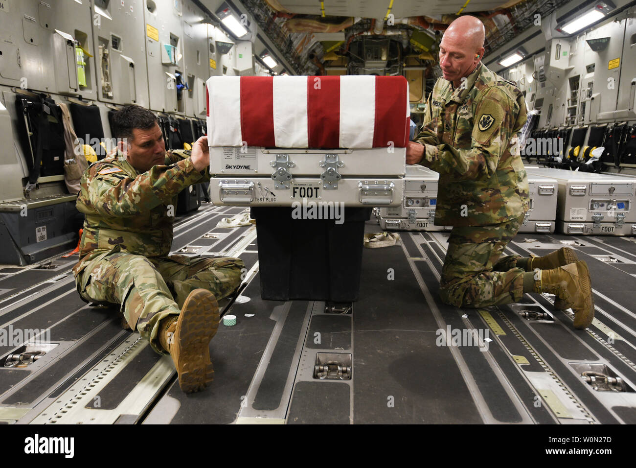 U.S. Army Staff Sgt. Marc Weyrick, Links, und Sgt. 1. Klasse Eric Feltz, leichenhalle Affairs Spezialisten zugewiesen, um die Verteidigung POW/MIA Accounting Agentur (DPAA), eine US-Flagge auf ein Verteilergetriebe an Bord einer Air Force C-17 Globemaster III de Route zu Joint Base Pearl Harbor-Hickam, Hawaii, von Osan Flughafen, Republik Korea, am 1. August 2018. Die Fälle enthalten möglich bleibt der Service Mitglieder während des koreanischen Krieges verloren und wurden zur forensischen DPAA's Laboratory in Hawaii übertragen die Identifikation zur Unterstützung der Mission der Agentur die möglichst vollständige Kont oinformationen zu beginnen. Stockfoto