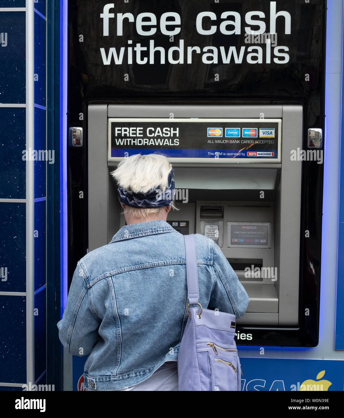 Frau mit ATM Maschine mit kostenlosen Bargeldbezug Dienstleistungen Schottland, Großbritannien Stockfoto