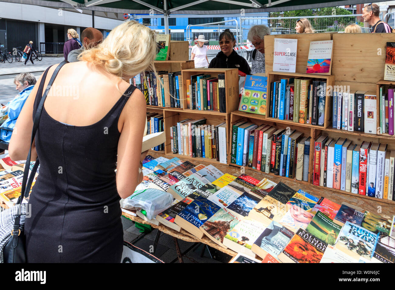 Eine Frau sucht die Titel auf eine zweite-Hand buch Stand beim Markt am Samstag in Navigator Square, Torbogen, nördlich von London, UK, 2019 Stockfoto