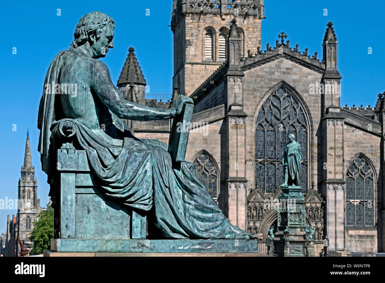Die Statue des David Hume von Bildhauer Alexander Stoddart auf der Royal Mile in Edinburgh bei St Giles Kathedrale im Hintergrund. Stockfoto
