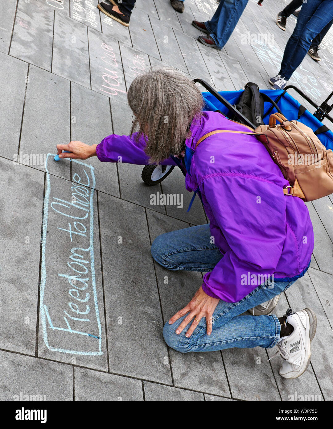Eine Frau schreibt in Kreide „Freedom to Choose“ während der Frauenrechtskundgebung 2019 auf dem Public Square in Cleveland, Ohio, USA. Stockfoto