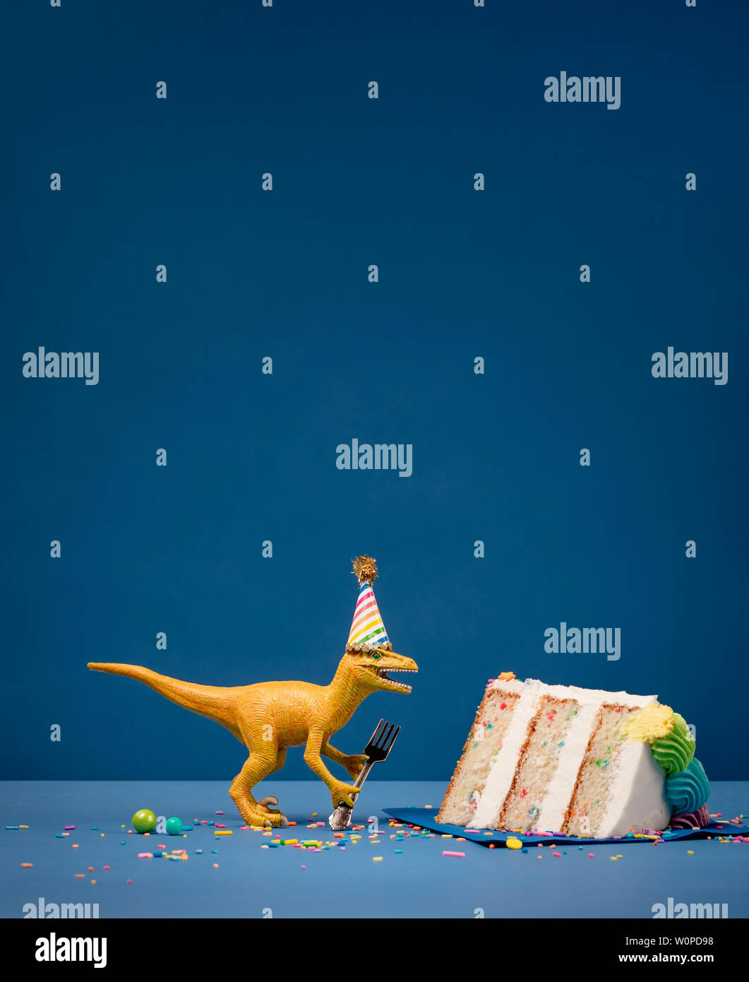 Spielzeug Dinosaurier Holding eine Gabel neben einem Stück Torte auf einem blauen Hintergrund mit Copyspace. Stockfoto