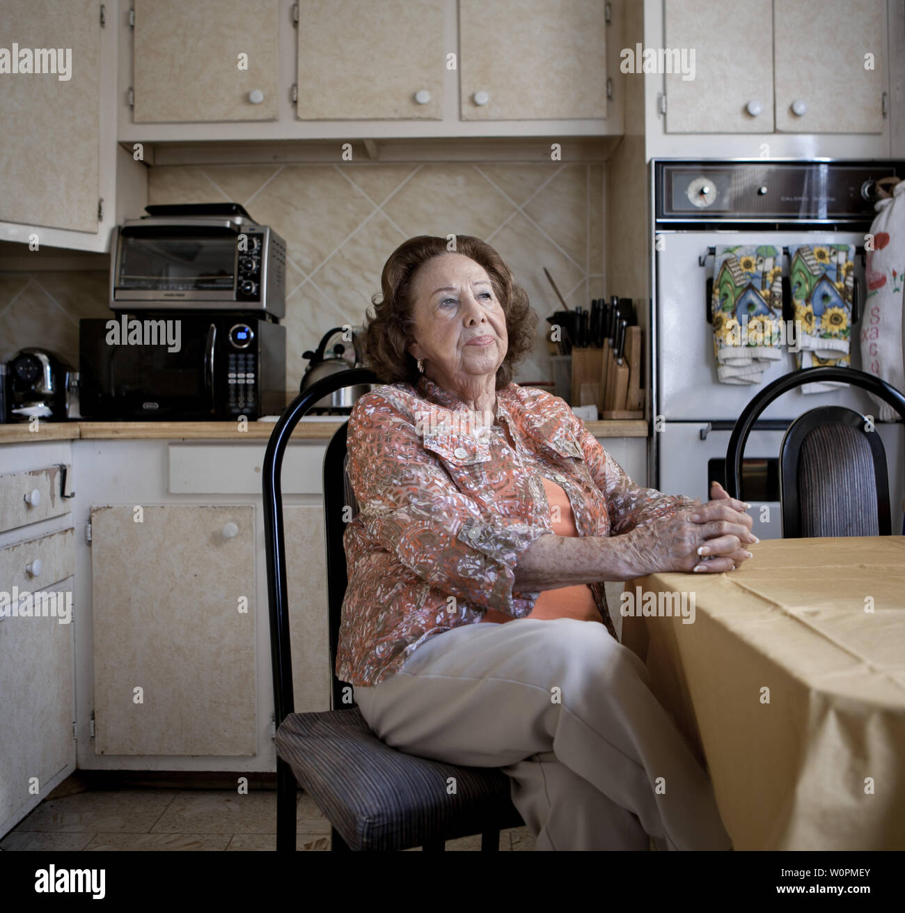 Eine ältere Frau sitzt in Ihrem altmodischen Küche Stockfoto