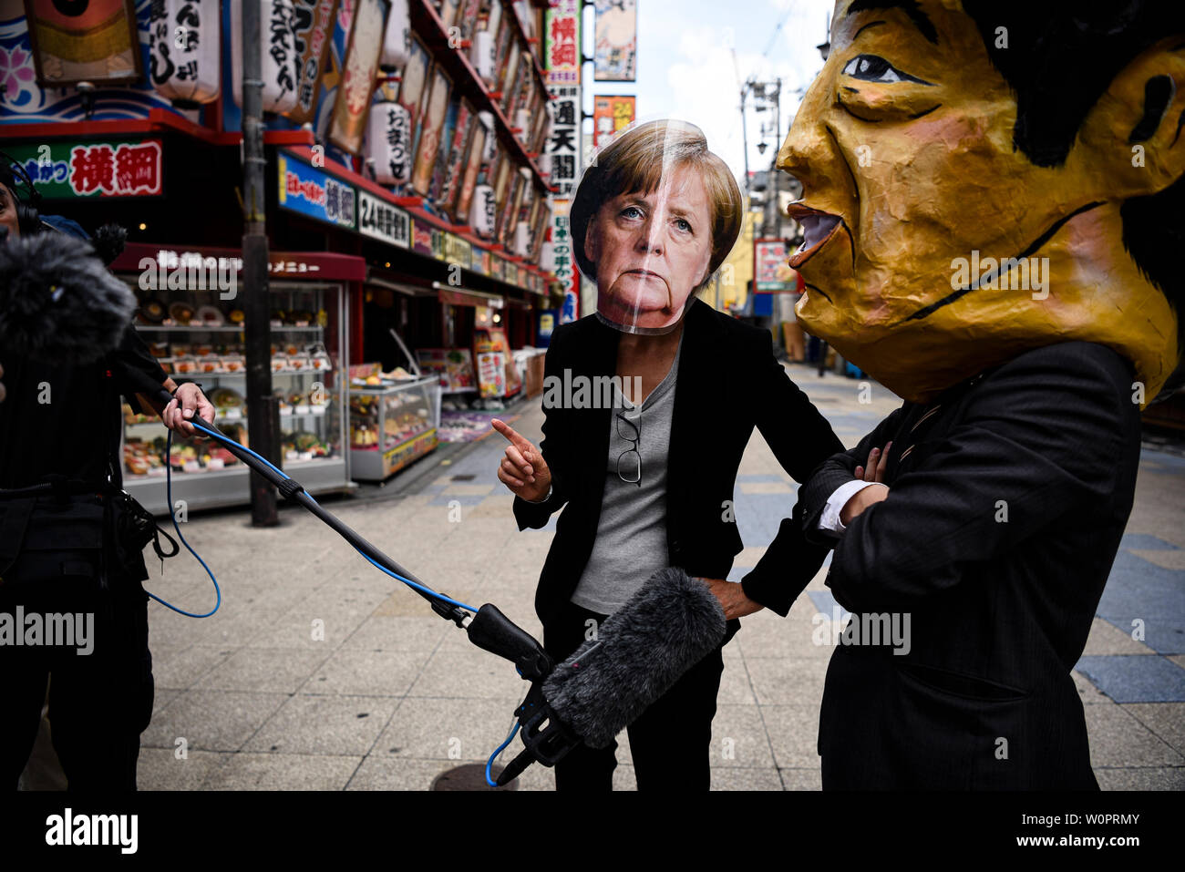 Osaka, Japan. 28 Juni, 2019. Die Demonstranten tragen Masken von Bundeskanzlerin Angela Merkel und der japanische Ministerpräsident Shinzo Abe sprechen Sie mit den Medien auf einen Protest gegen Kohle macht während der G20-Gipfel in Osaka, Japan. Credit: Ben Weller/LBA/Alamy leben Nachrichten Stockfoto