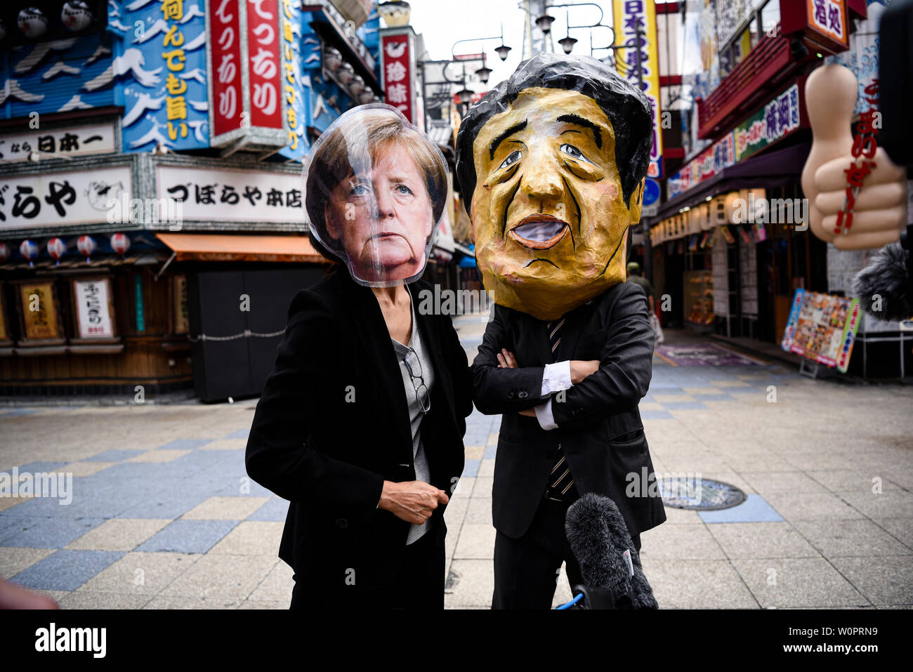 Osaka, Japan. 28 Juni, 2019. Die Demonstranten tragen Masken von Bundeskanzlerin Angela Merkel und der japanische Ministerpräsident Shinzo Abe sprechen Sie mit den Medien auf einen Protest gegen Kohle macht während der G20-Gipfel in Osaka, Japan. Credit: Ben Weller/LBA/Alamy leben Nachrichten Stockfoto