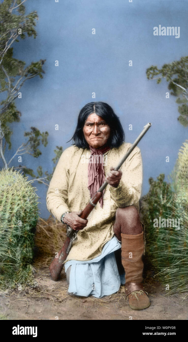 Ein koloriertes historisches Foto eines Anführers der Ureinwohner Amerikas, der in traditioneller Kleidung im Freien kniet und das kulturelle Erbe und die Stärke zeigt. Chiricahua apace Indianer Geronimo (Goyathly) kniend mit Gewehr - Geronimo war ein prominenter Anführer und Medizinmann aus der Bedonkohe-Band des Apachen-Stammes. Von 1850 bis 1886 schloss sich Geronimo mit Mitgliedern von drei anderen Chiricahua Apache-Bands – den Tchihende, den Tsokanende und den Nednhi – an, um zahlreiche Überfälle durchzuführen sowie gegen mexikanische und US-amerikanische Militärkampagnen in den nordmexikanischen bundesstaaten Chihuahua und Sonora zu kämpfen. Stockfoto