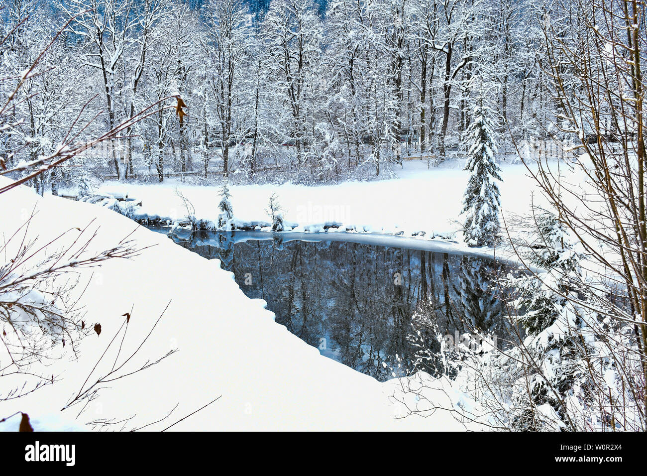 Malerisch verschneite Landschaft und unberührte reflektierenden See unter den Wald in Bayern Deutschland. Stockfoto