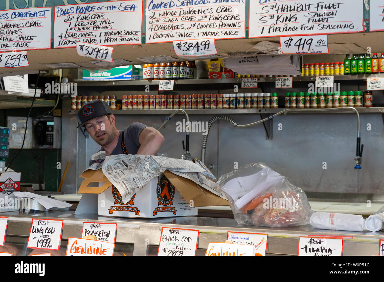Vereinigte Staaten von Amerika, USA, Seattle, Washington, Pike Place, 10. Mai 2019. Verkäufer Verpackung von frischem Fisch in den öffentlichen Markt steht verkaufen Stockfoto