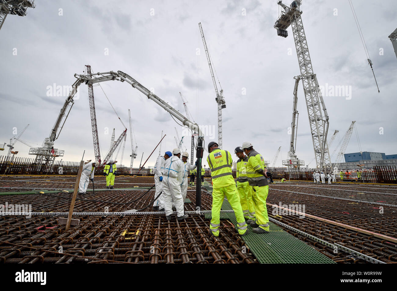 Bauarbeiter stehen auf der Unterseite zum ersten Reaktor in Hinkley Point C Power Station in der Nähe von Bridgwater, Somerset, einem riesigen kreisförmigen Masse von verstärktem Stahl, wie es mit dem Großbritannien der größte jemals gießen Beton, rund 9'000 M3 gefüllt ist. Stockfoto