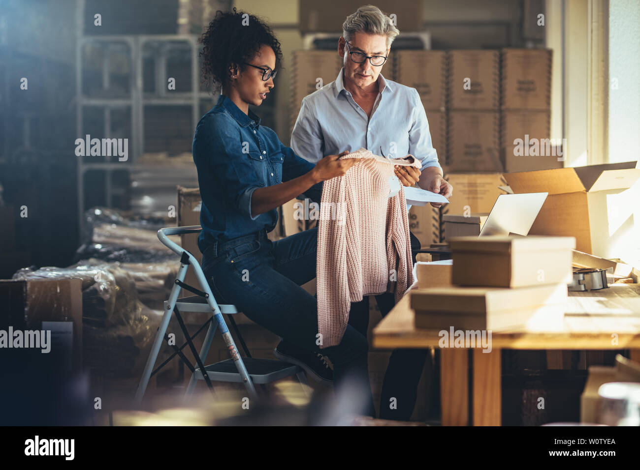 Frau, das Produkt zu Ihrem Partner vor dem Verpacken und dem Kunden übergeben wird. Online Vertrieb von Business Partnern zusammen in den offic arbeiten Stockfoto