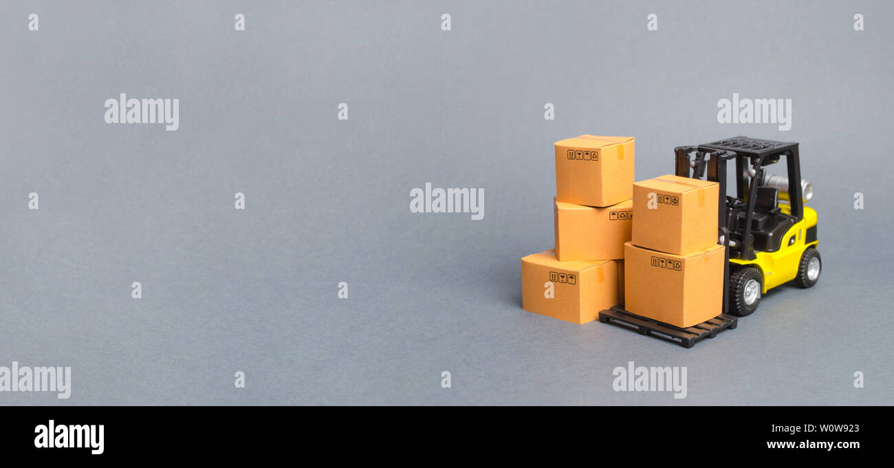 Gelbe Gabelstapler mit Kartons. Service Lagerung von Waren in einem Lagerhaus, Lieferung und Transport. Fracht und Lieferung. Importieren Sie ein Stockfoto